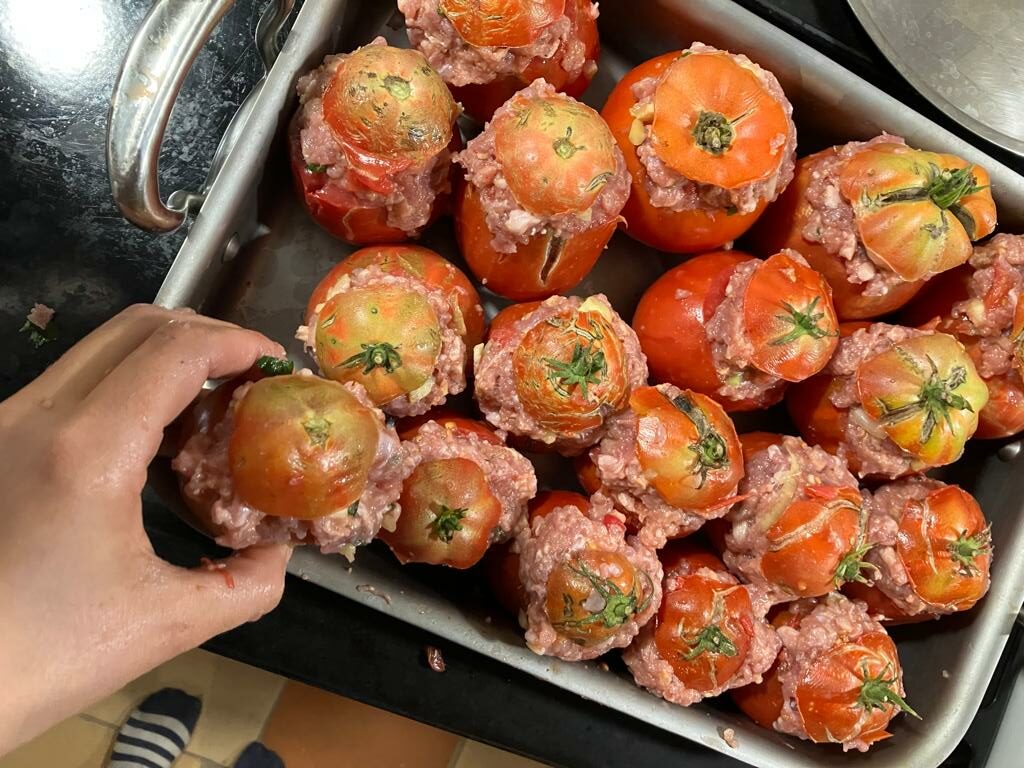 Main déposant une tomates dans un plat de tomates farcies