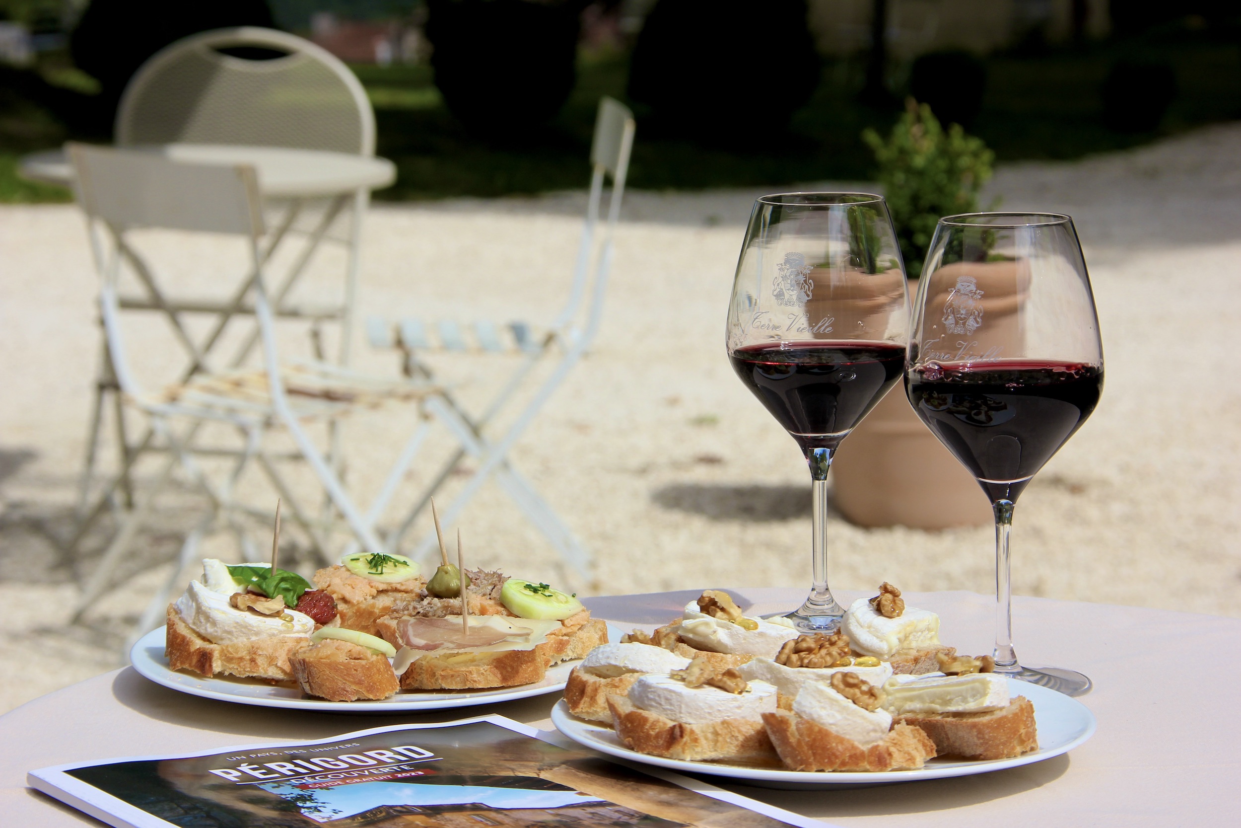 Deux assiettes de tapas et pintxos façon pays basque sur une table à côté de deux verres de vin rouge à la robe sombre